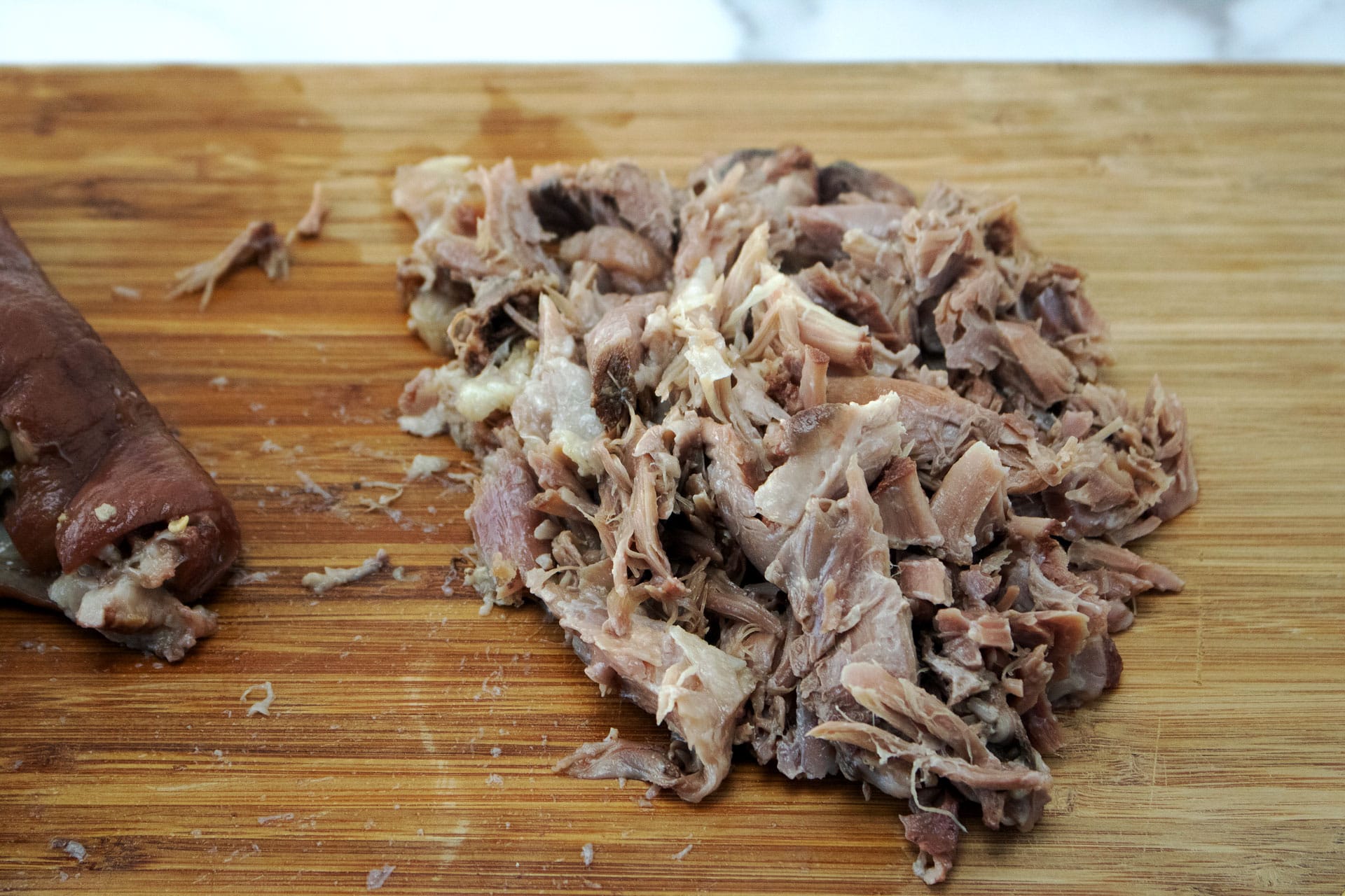 Shredded ham hock meat on a wooden cutting board