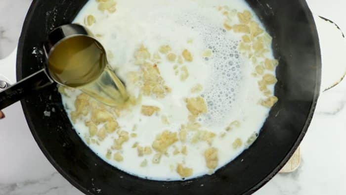 adding broth to the creamed corn