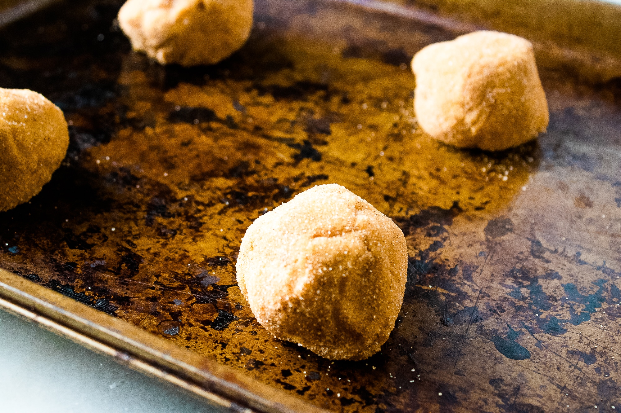 Cinnamon sugar coated pumpkin snickerdoodle dough balls on a baking sheet