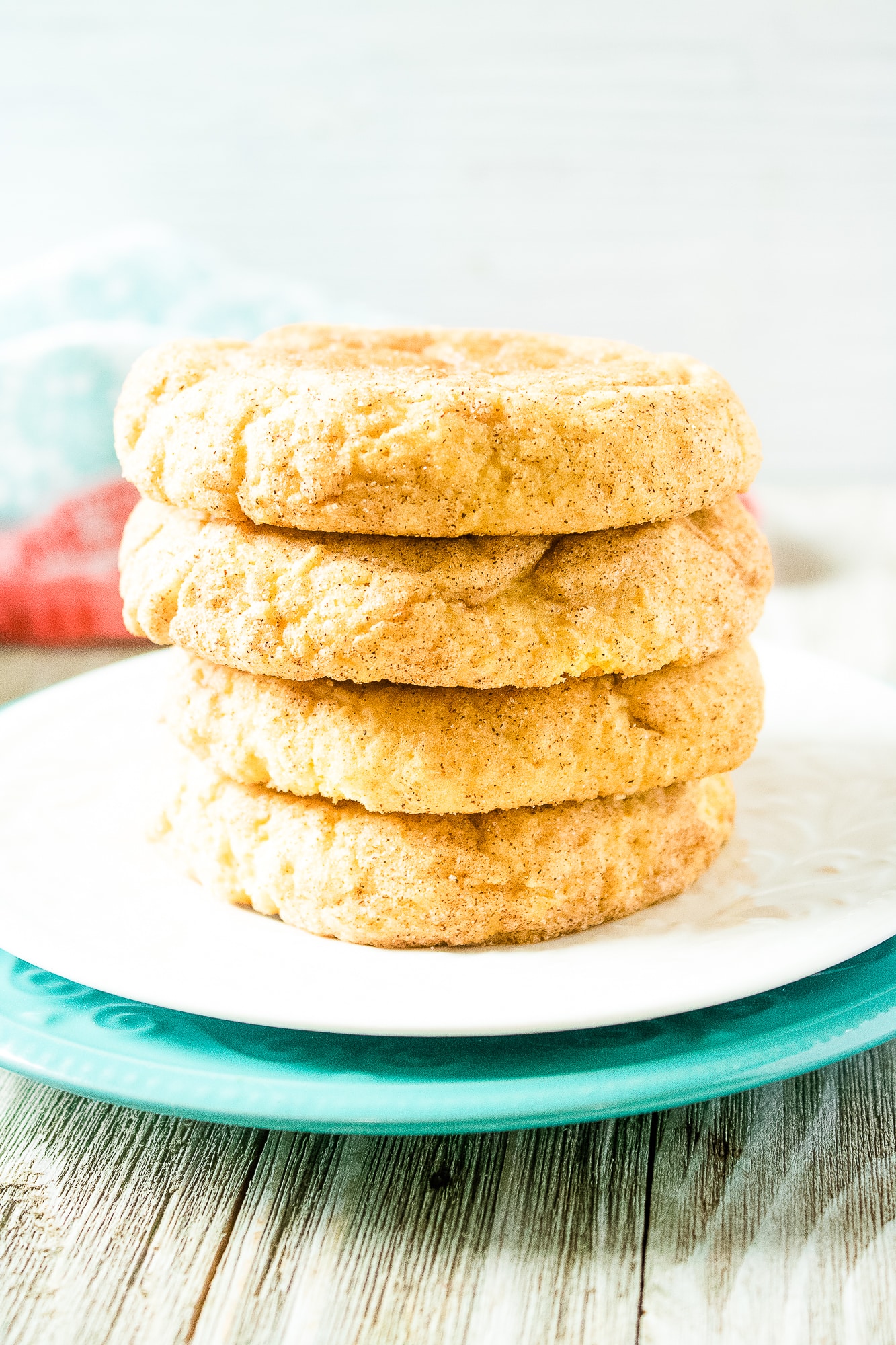 Four pumpkin snickerdoodle cookies stacked on a white plate