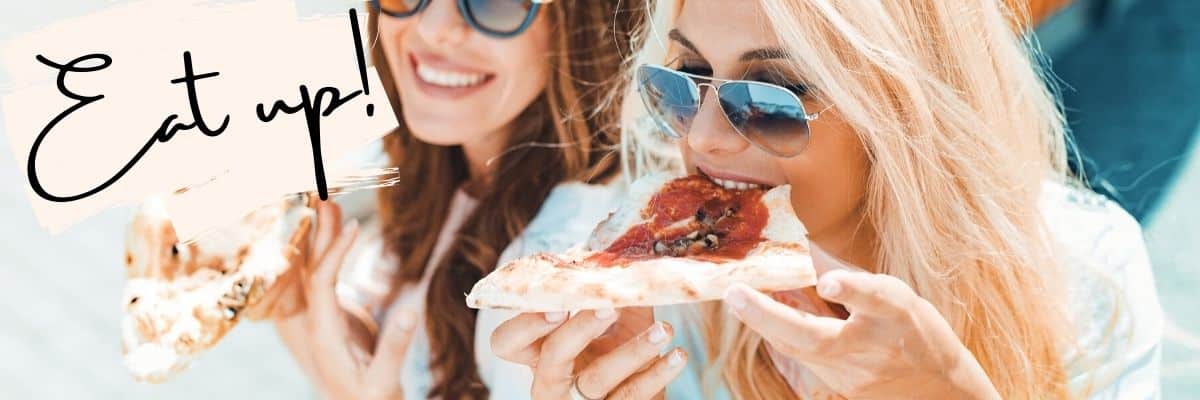 two women eating pizza and laughing