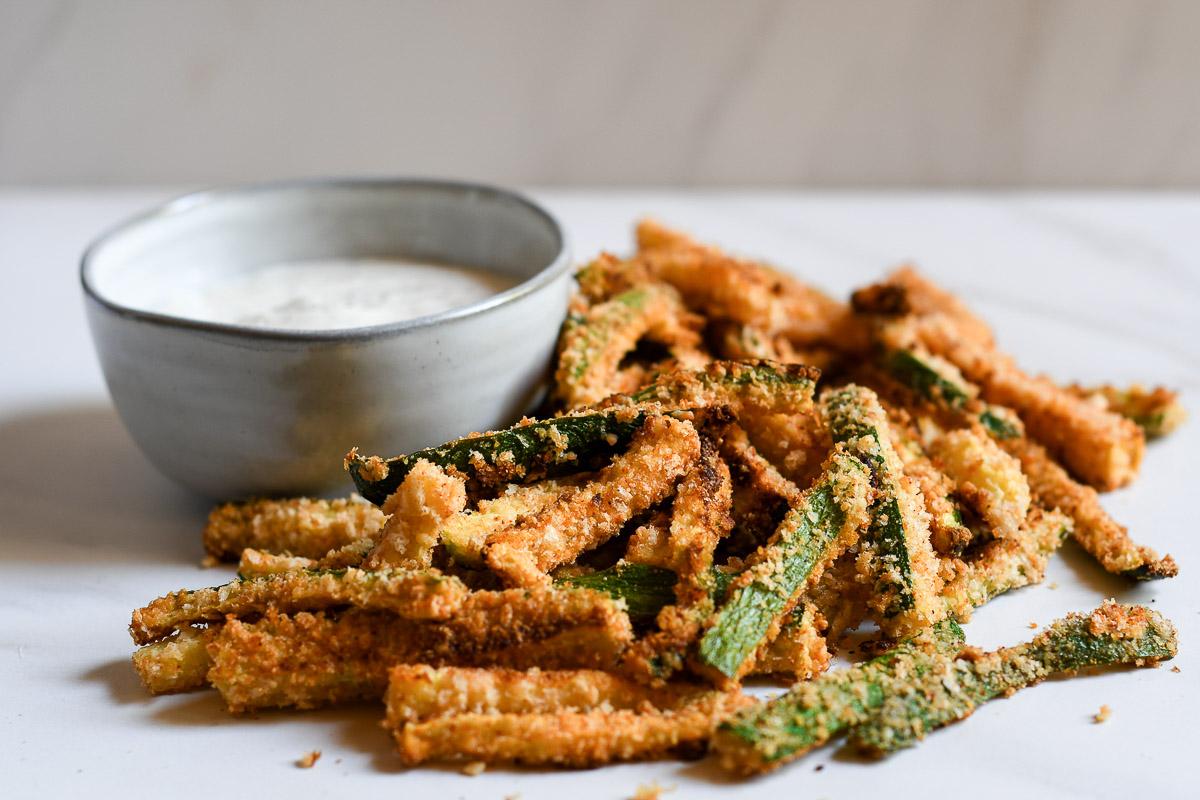 zucchini fries being served on a white table