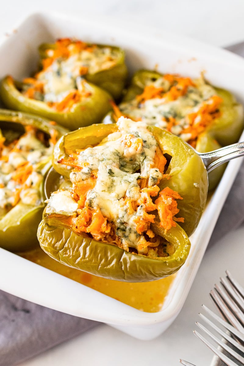 buffalo chicken stuffed peppers being spooned out of pan