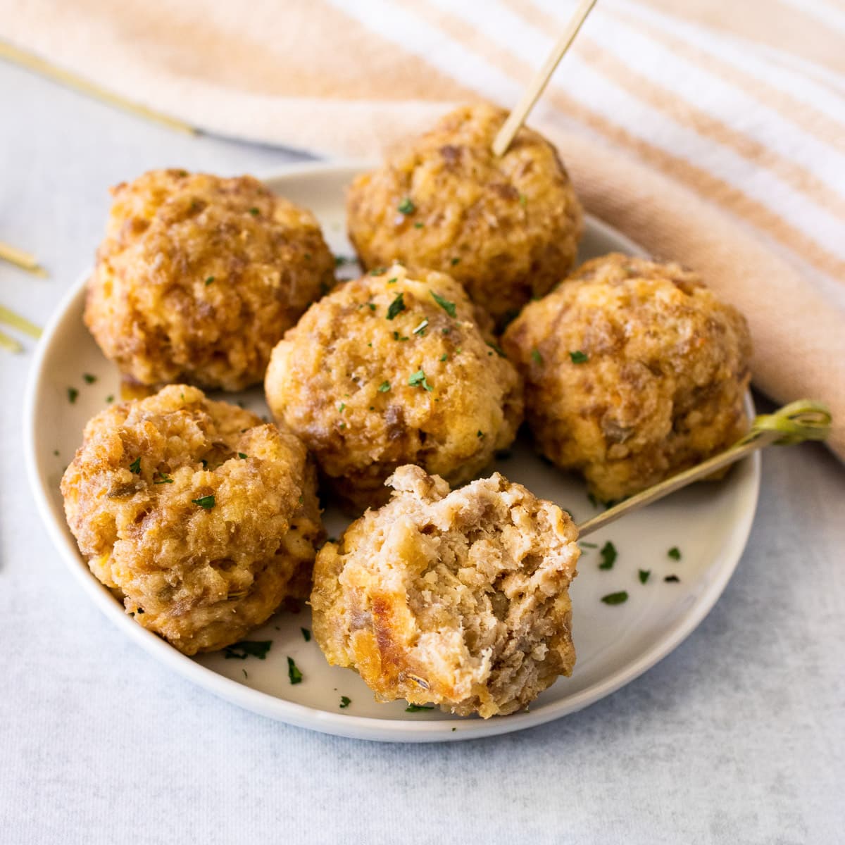 close up plate of cream cheese sausage balls with bite out and toothpicks