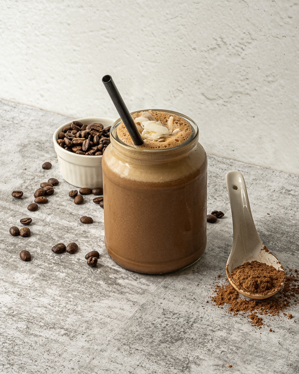 side view chocolate protein shake in a jar on a table with a straw