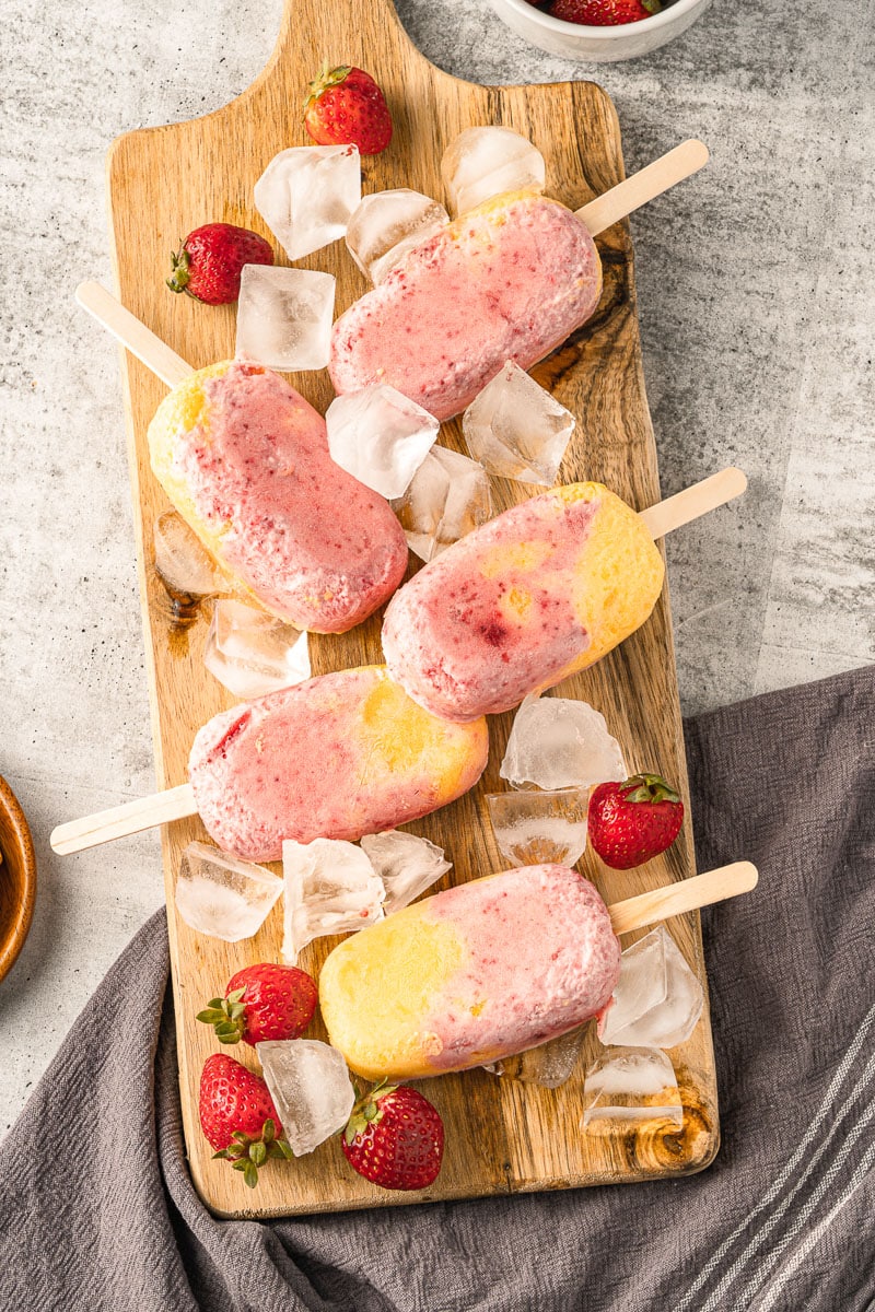 strawberry mango popsicles on a wooden platter