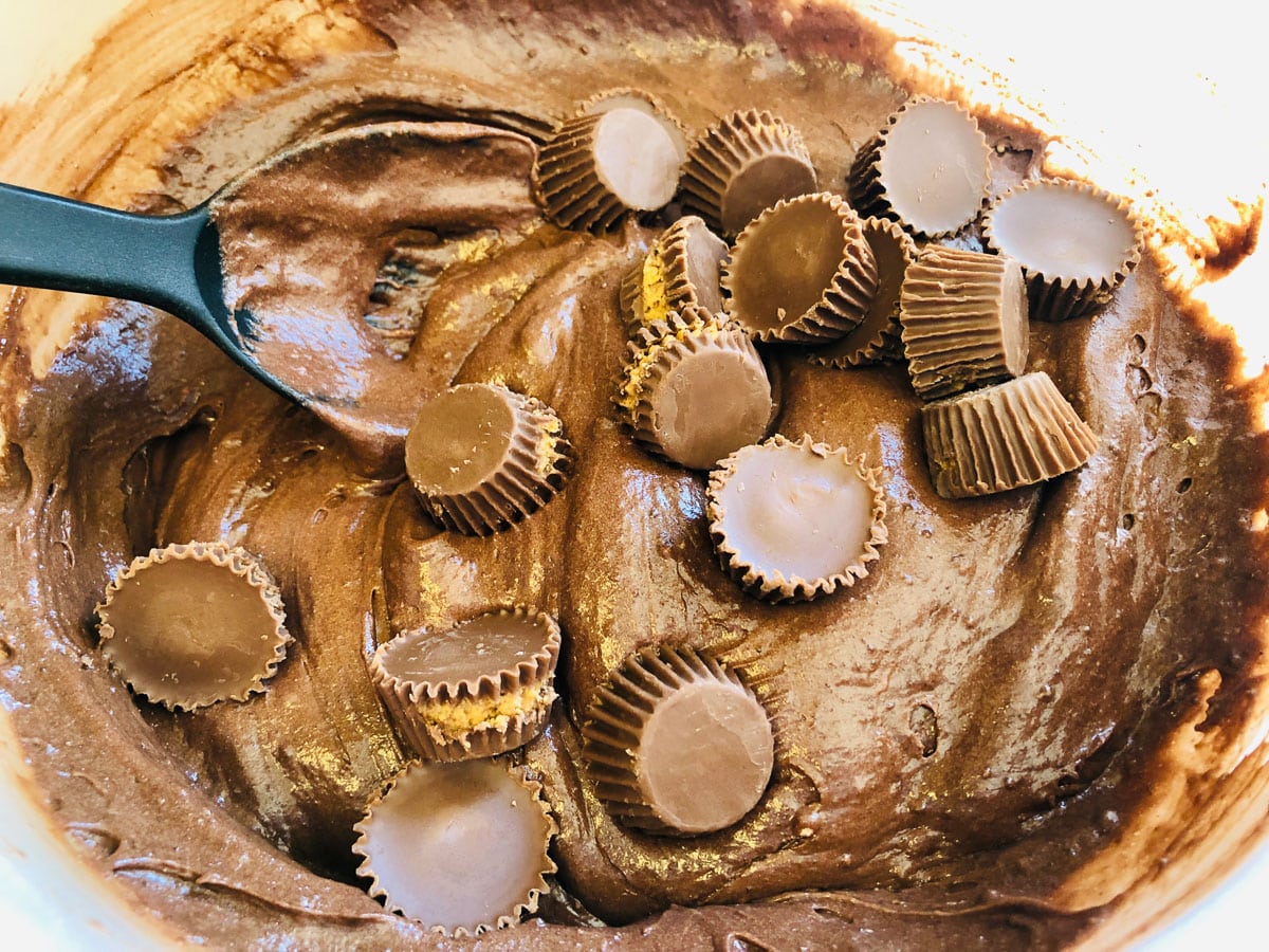 mixing mini Reeses cups into batter for chocolate peanut butter cake