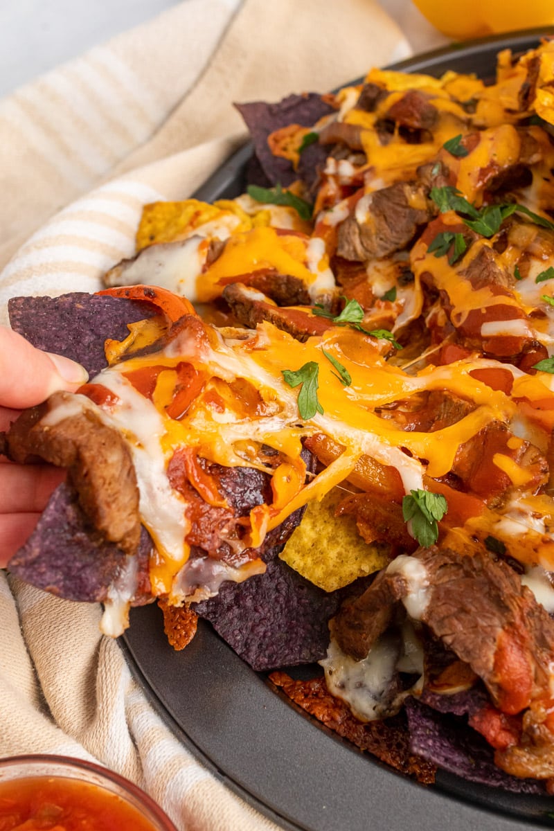 close up of hand grabbing one-pan fajita nachos