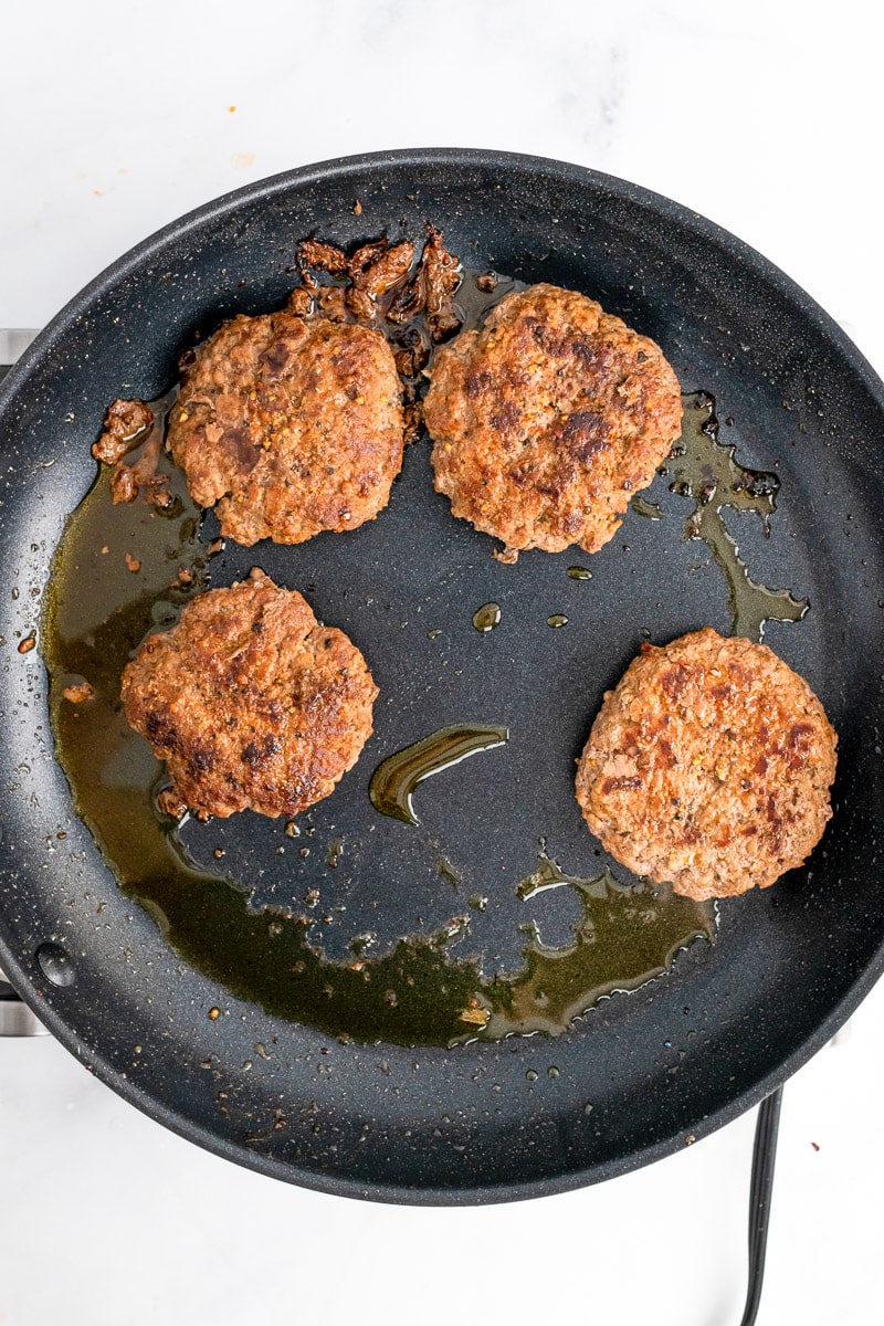 homemade burgers cooking in a skillet