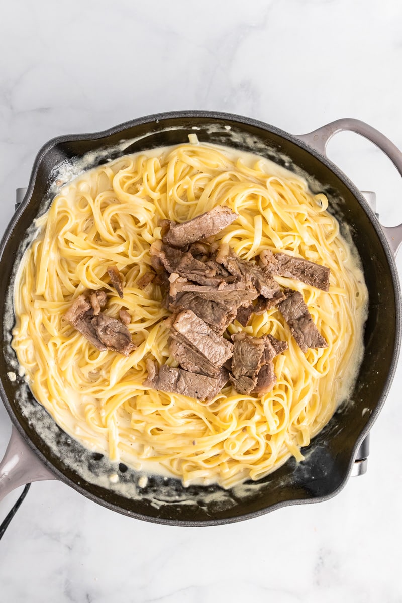 skillet of easy steak alfredo noodles with pile of steak