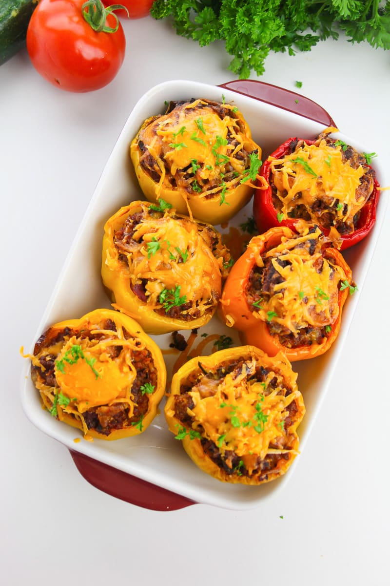 six keto stuffed peppers in a white baking tray with red handles
