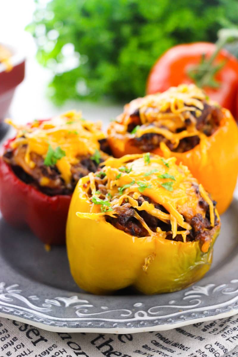 close up red, orange, and yellow keto stuffed peppers on white plate