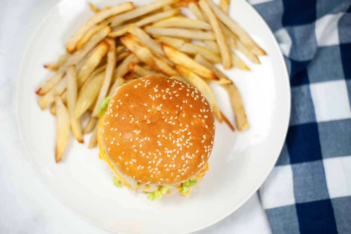 top view of copycat Big Mac with sauce on white plate with fries