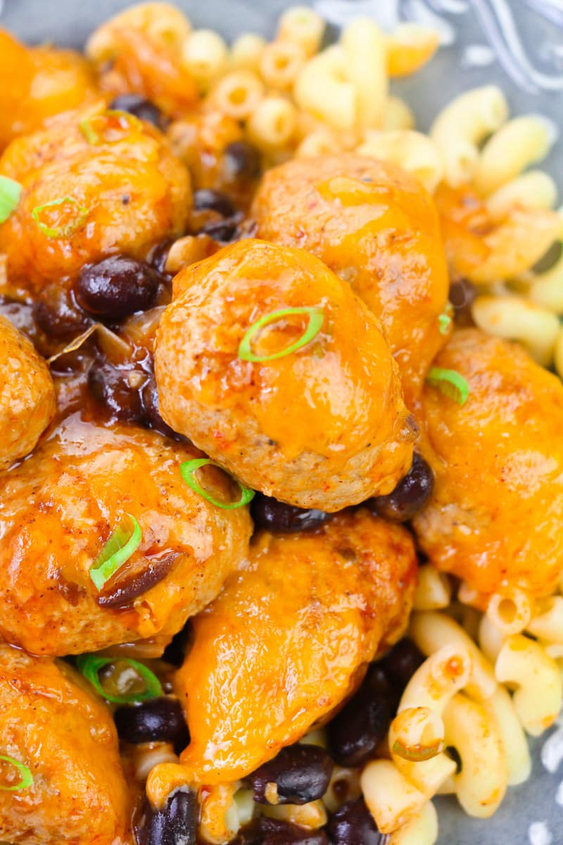 close up of cheesy enchilada meatballs served over macaroni pasta