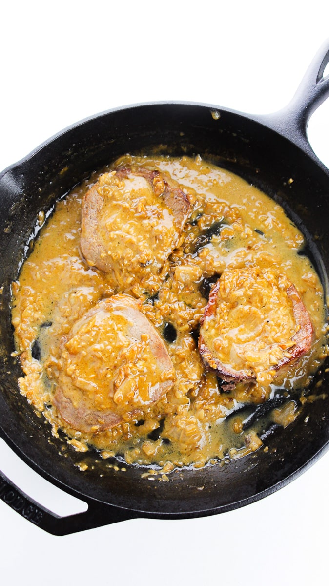 easy smothered steaks cooking in gravy on skillet