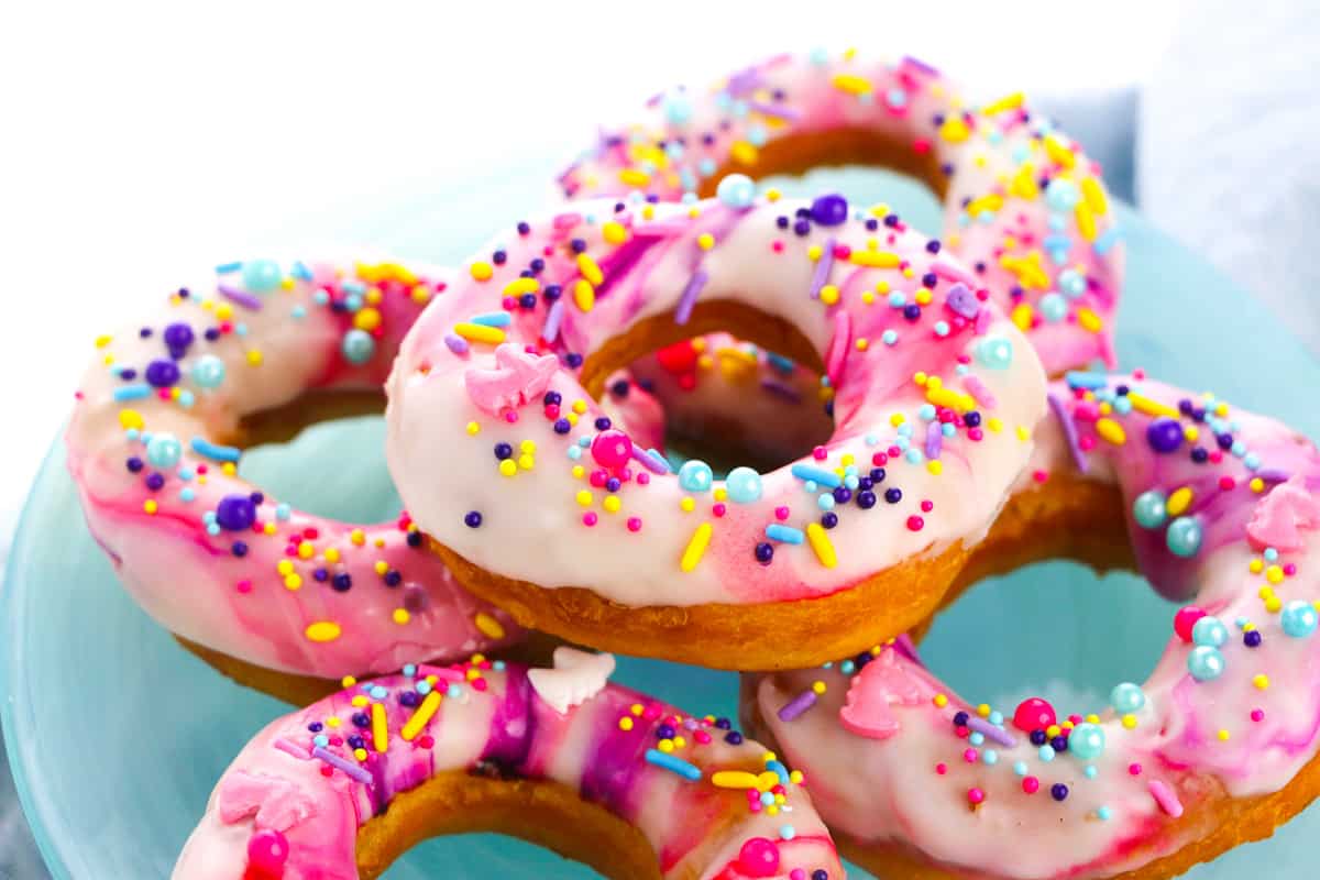 side view stack of unicorn donuts on blue plate