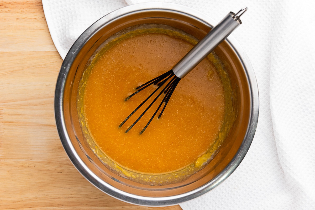 Pumpkin puree, milk, melted butter, and sugar whisked together in a metal mixing bowl