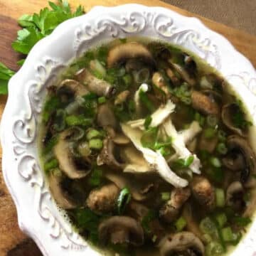Chicken marsala soup with mushrooms, shredded rotisserie chicken and green onions in a white bowl