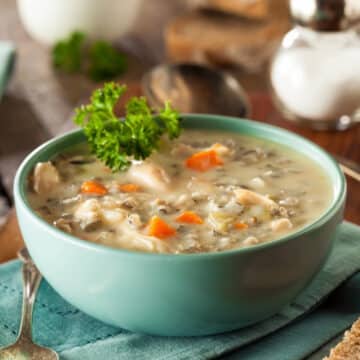 Copycat Panera creamy chicken and wild rice soup in a teal bowl with parsley