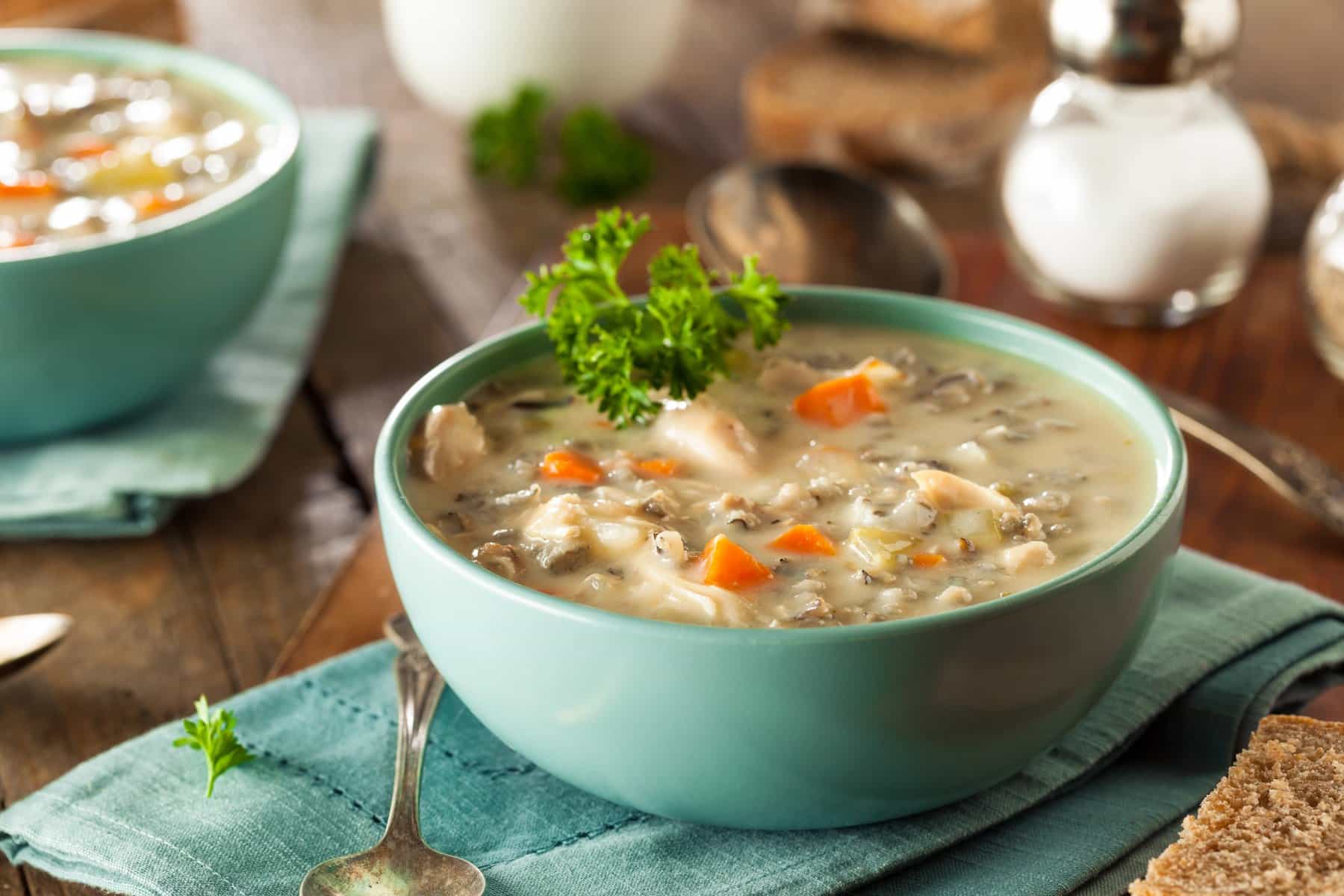 Close-up of copycat Panera creamy chicken and wild rice soup in a teal bowl garnished with parsley