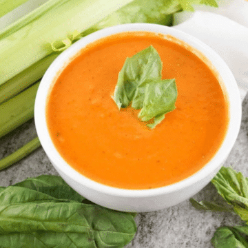 Copycat Panera tomato soup in a white bowl topped with fresh basil
