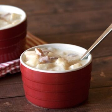 Creamy ham and potato soup with heavy cream in a red ramekin with a spoon