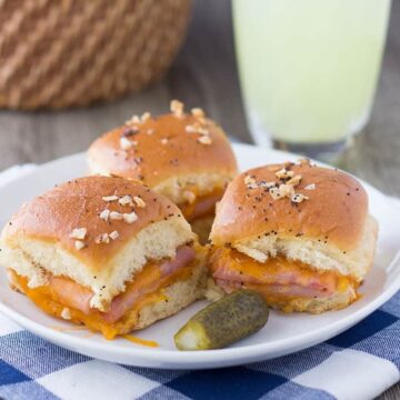 Ham and cheddar potluck slider sandwiches with a pickle and lemonade, square crop