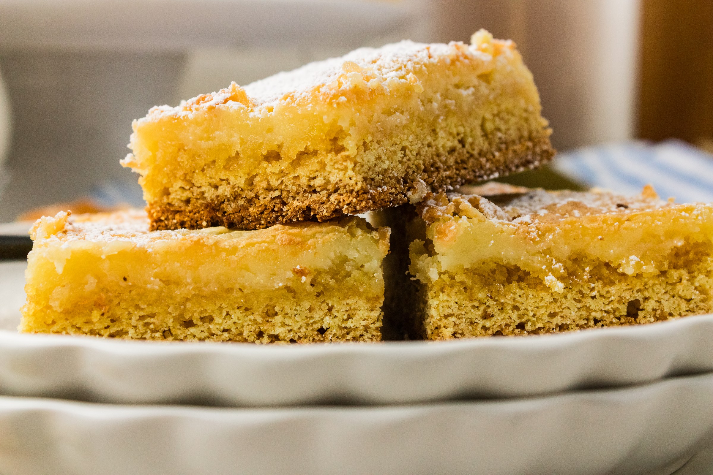 Neiman Marcus cake squares stacked on a white plate showing the gooey cream cheese layer