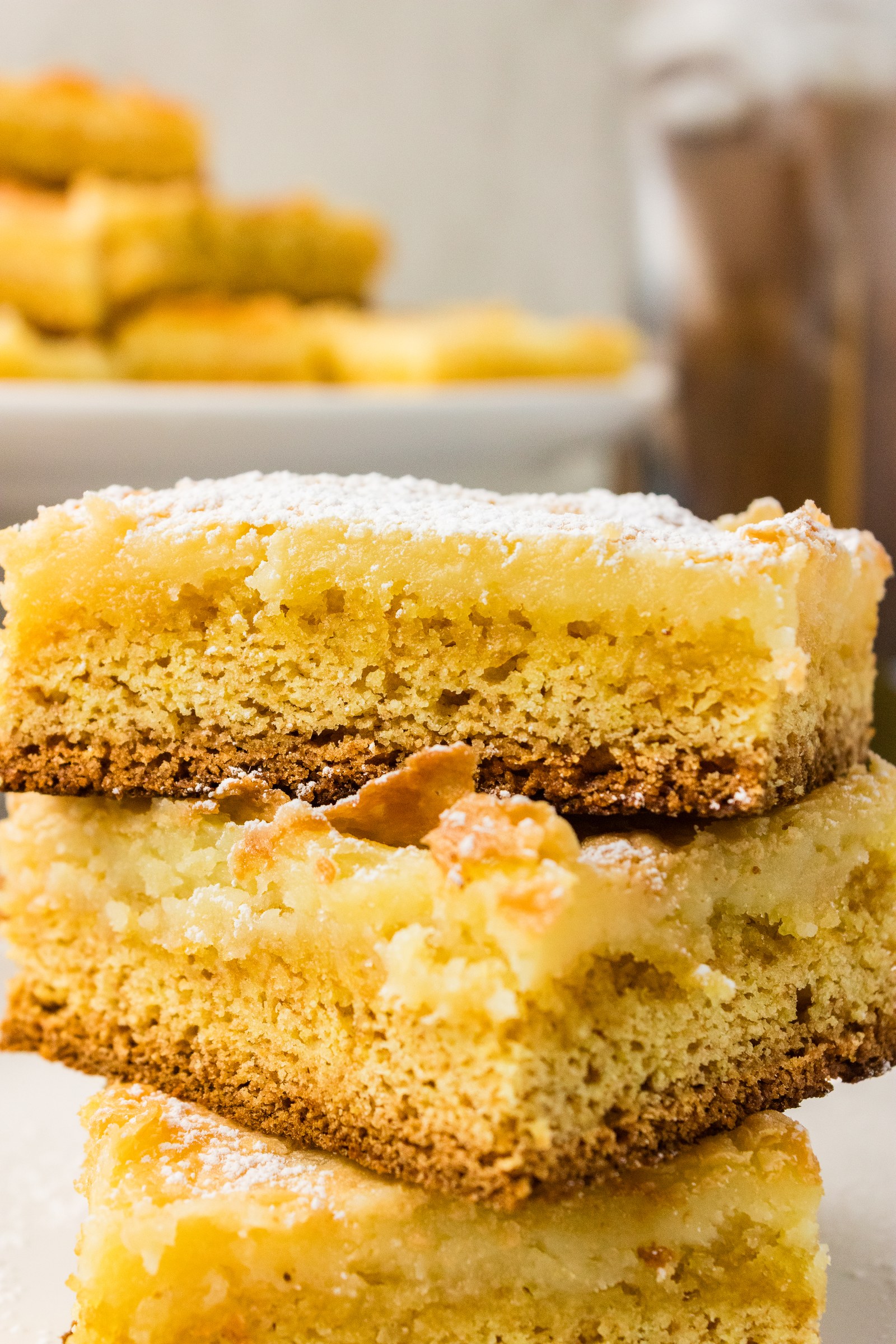 Close-up of stacked gooey butter cake squares showing the cake mix crust and soft cream cheese layer