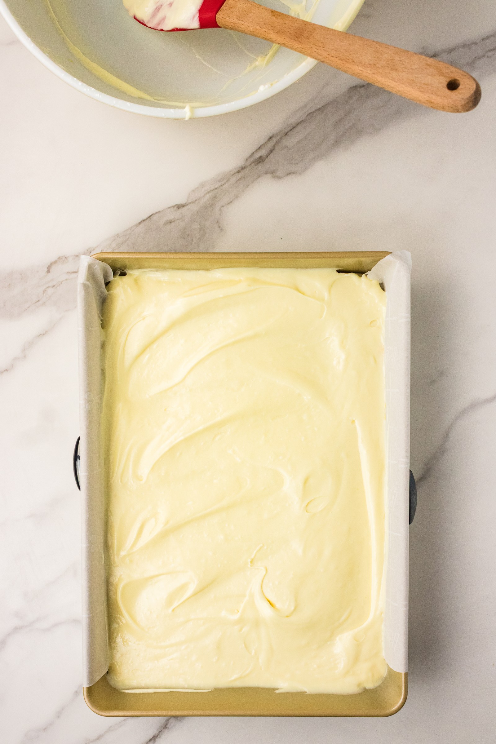 Cream cheese topping spread over the cake mix crust in a baking pan before baking