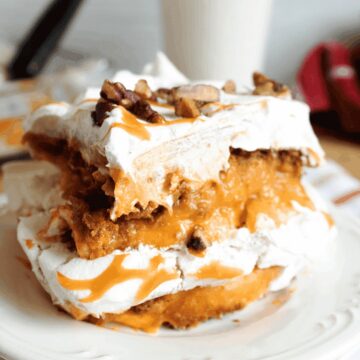 A slice of no-bake pumpkin lasagna dessert with gingersnap, pumpkin and whipped cream cheese layers, topped with caramel and pecans