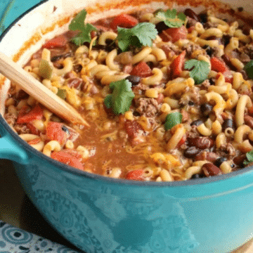 One-pot chili mac and cheese with beans, ground beef, and cilantro in a blue Dutch oven