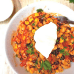 One-pot southwest chili mac in a white bowl topped with sour cream and cilantro