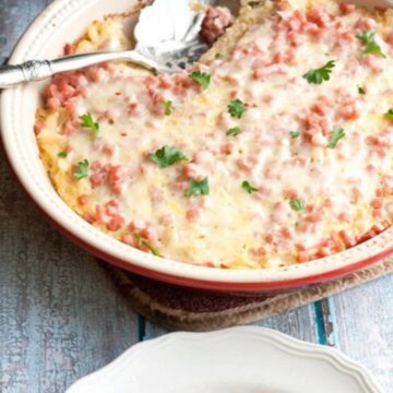 Overnight southwest breakfast casserole with diced ham and melted pepper jack cheese in a red baking dish