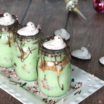 Pistachio trifles layered in mason jars with chocolate drizzle, crushed peppermint and candy cane Peeps on top