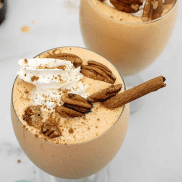 Pumpkin cheesecake milkshake topped with whipped cream, pecans and a cinnamon stick