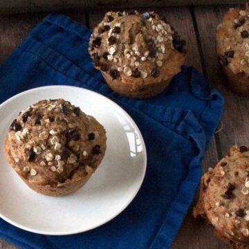 Pumpkin chocolate chip muffins with oat and chocolate chip topping on a blue napkin
