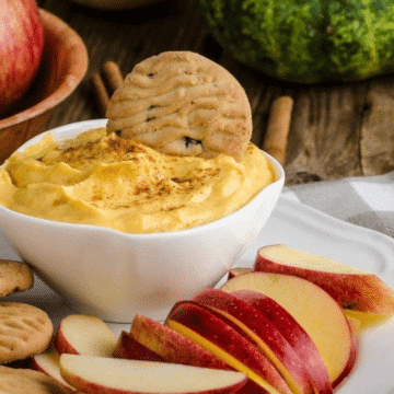 Pumpkin cream cheese filling in a white bowl with apple slices and cookies