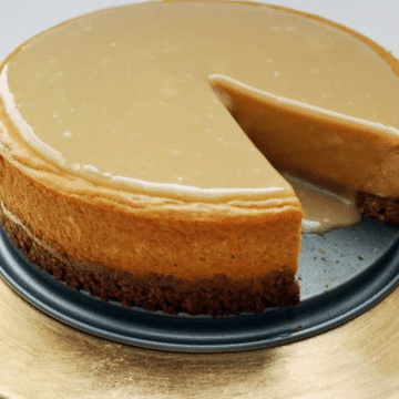 Pumpkin maple cheesecake with a slice cut out, showing the pecan oat crust and maple glaze