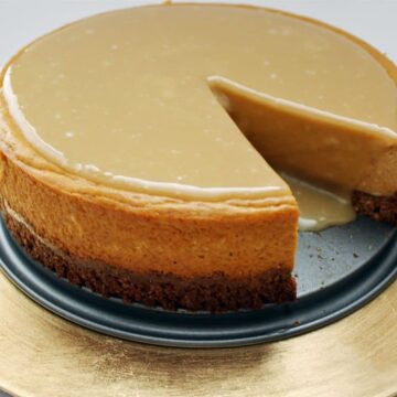 Pumpkin maple cheesecake with a slice removed, showing the pecan oat crust and glossy maple glaze