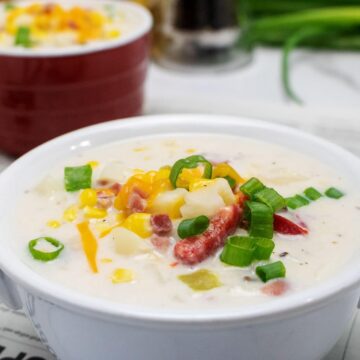Creamy slow cooker corn chowder with ham, corn and green onions in a white bowl