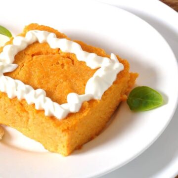 Square slice of Weight Watchers crustless pumpkin pie topped with whipped topping on a white plate